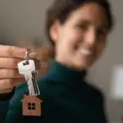 Smiling new homeowner posing by holding out her housekeys in front of her