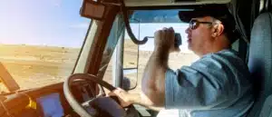 A truck driver driving while talking into his radio