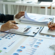 Close-up of two businesswomen calculating financial statements at a desk.