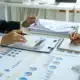 Close-up of two businesswomen calculating financial statements at a desk.